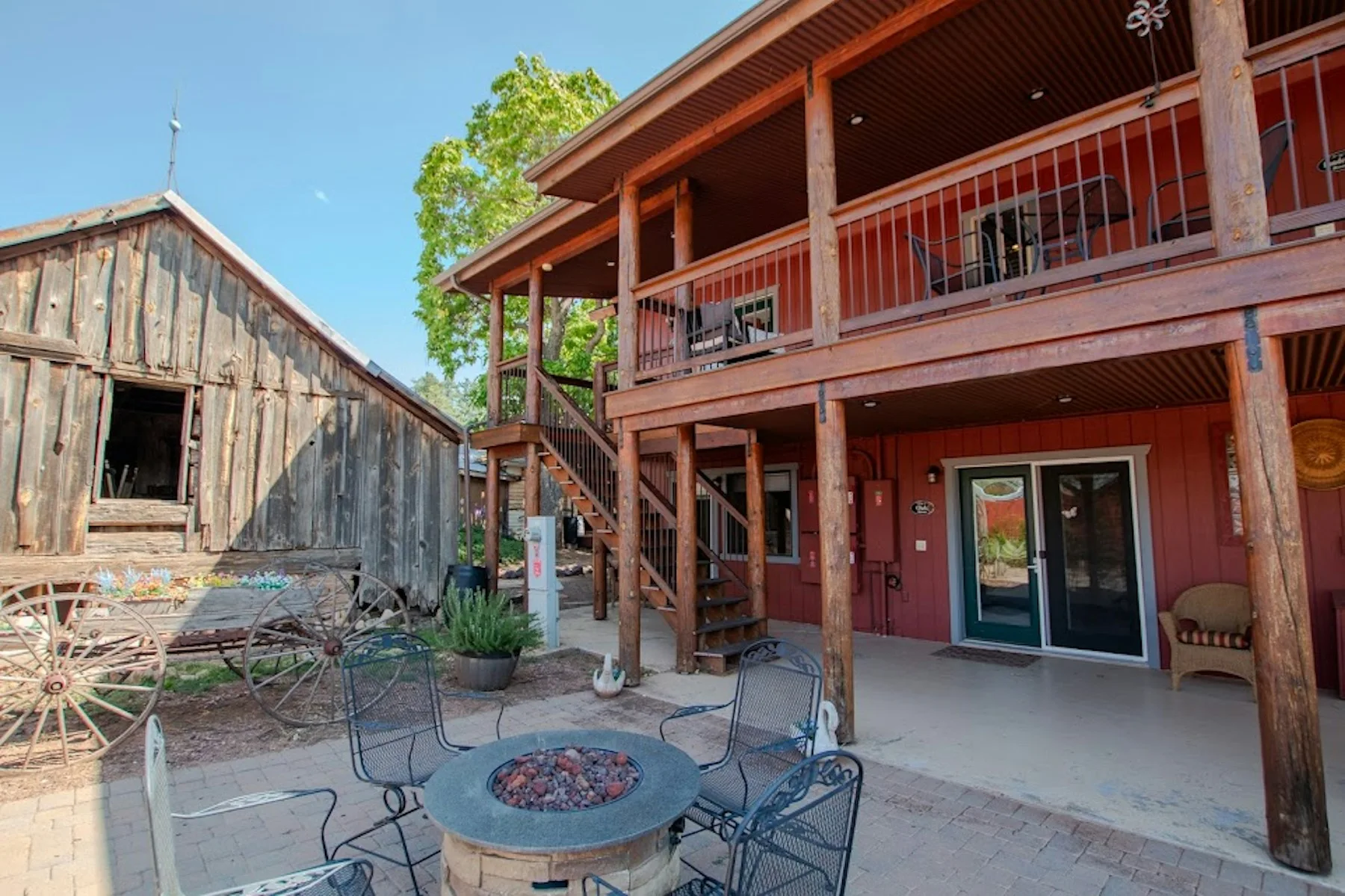 The red guest house, upper porch and shared courtyard beside a historic wooden cabin